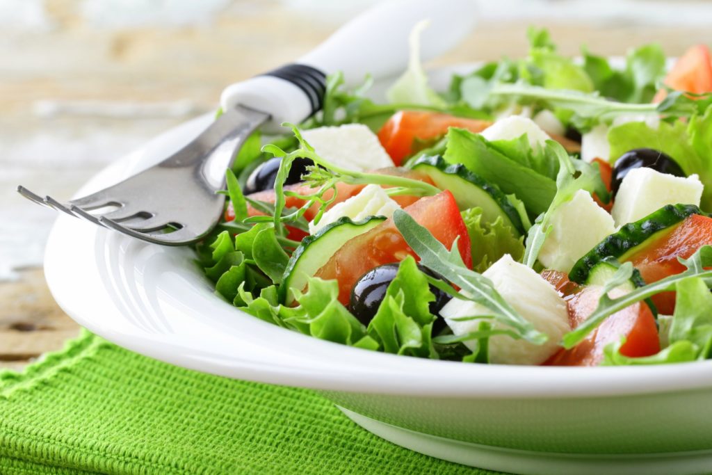 A fork sits on a bowl full of colorful salad.