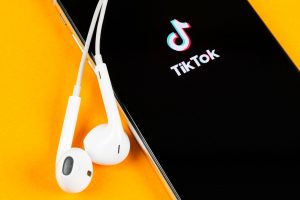 tiktok app being loaded on mobile iphone device with headphones plugged in
