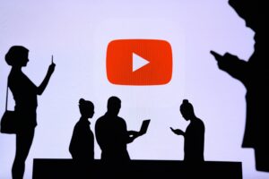 a youtube logo displays in the background with silhouettes of people on smart phones and laptops