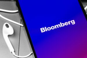 bloomberg application loading up current marketing events on a mobile smartphone on a table with earbuds connected