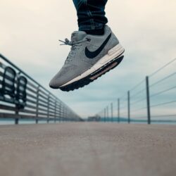 A man in Nike sneakers jumps into the air on a bridge. Image demonstrates a company with successful email marketing.